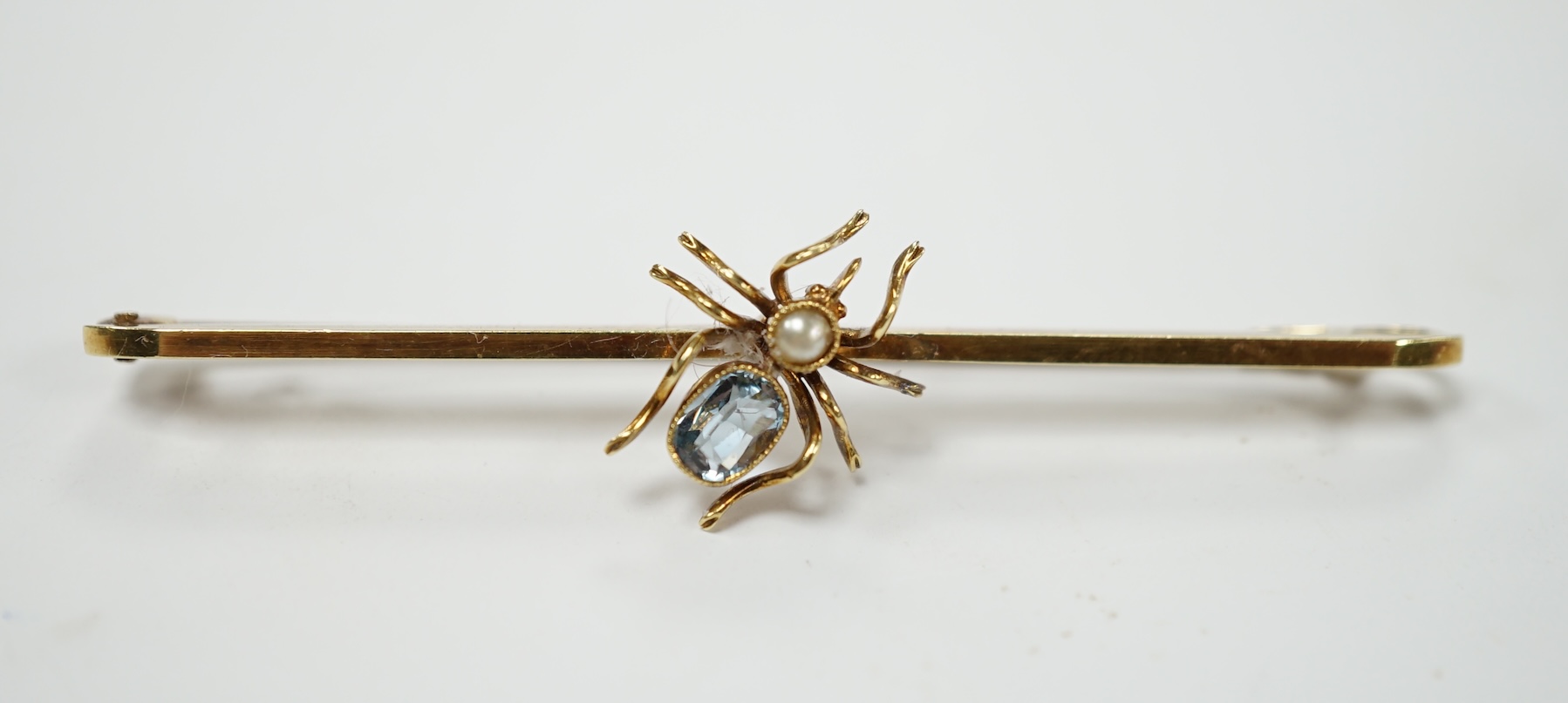 A yellow metal, aquamarine and seed pearl set spider bar brooch, 57mm, gross weight 3.5 grams. Good condition.